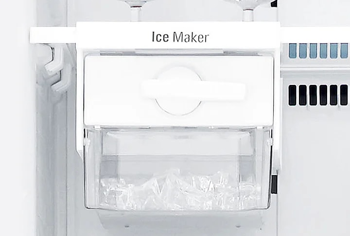 냉장고 내부에 설치된 얼음 제조기가 보입니다. Ice Maker라는 텍스트가 상단에 적혀 있으며, 투명한 용기 안에는 얼음이 담겨 있습니다. 주변은 흰색으로 깔끔하게 마감되어 있습니다.